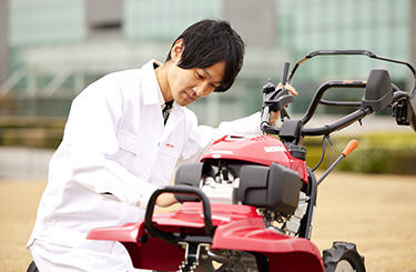 写真：赤い耕うん機をなでる木村さん